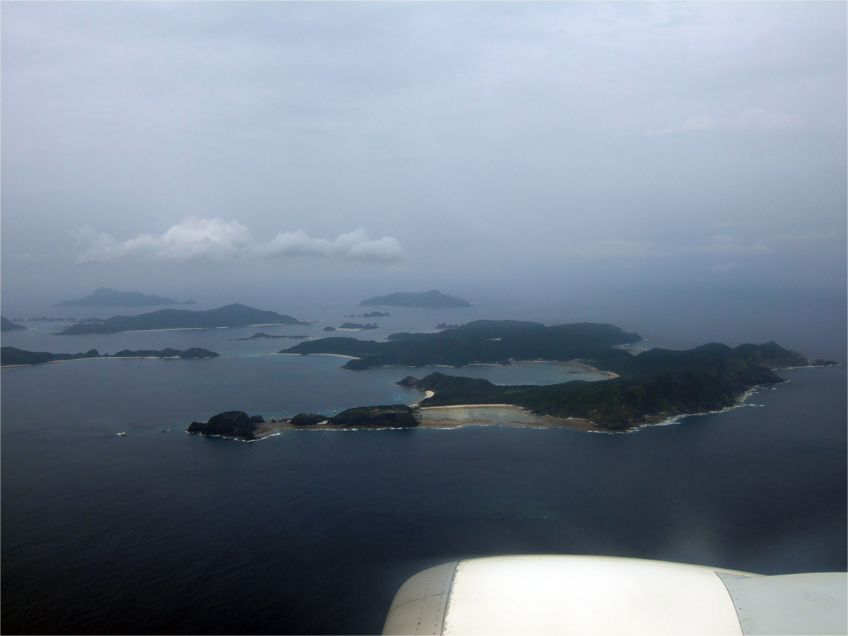 上空から見た座間味島．手前（下）が東，奥（上）が西方向．中央にトウマの浜が見える
