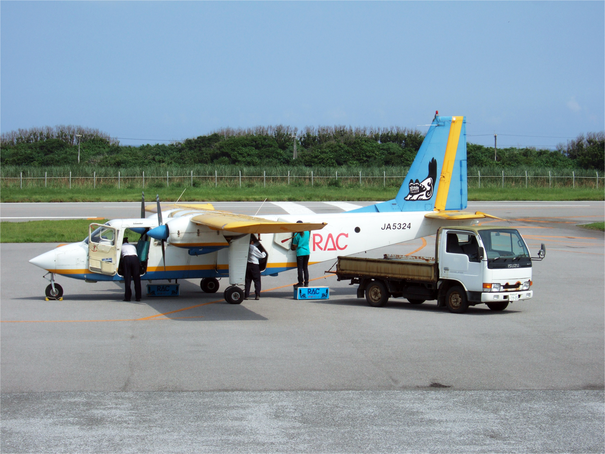 波照間空港にとまる琉球エアコミューターのアイランダーの機体．隣に横付けされている軽トラックに運んできた荷物を載せる．．飛行機から降りて空港に向かう途中に撮影